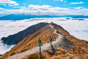 People walk along a mountain that is covered with clouds